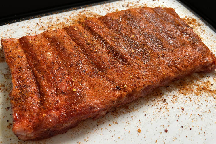 seasoned raw pork ribs on a white plate