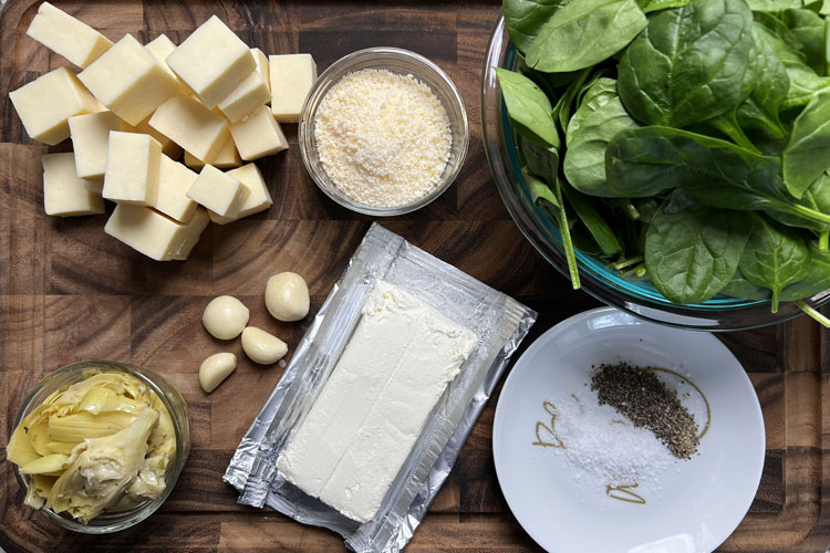 ingredients for smoked spinich dip laid out on a wooden chopping board