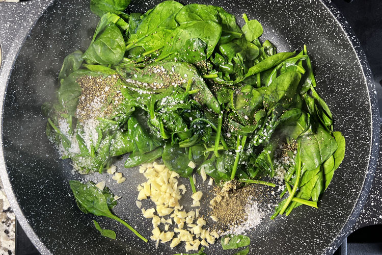 cooked spinich with garlic in a cast iron pan