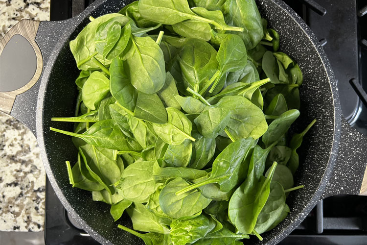 uncooked spinich in a cast iron pan