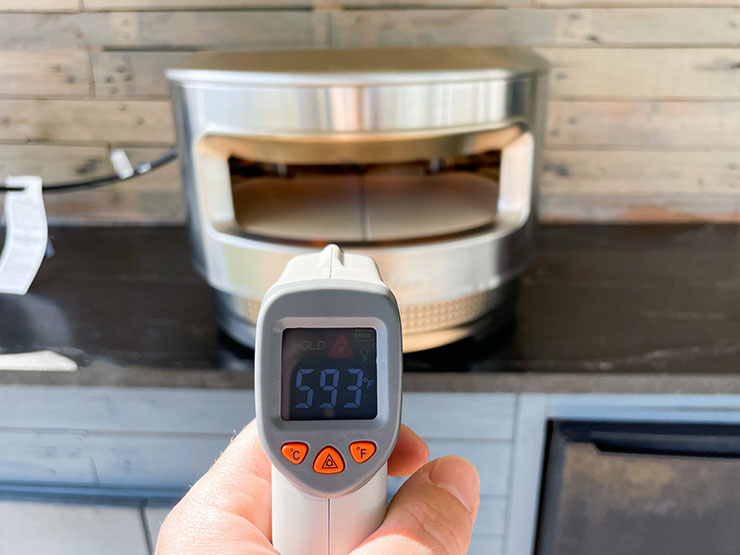 temperature gun pointing at the Solo Stove Pi pizza oven