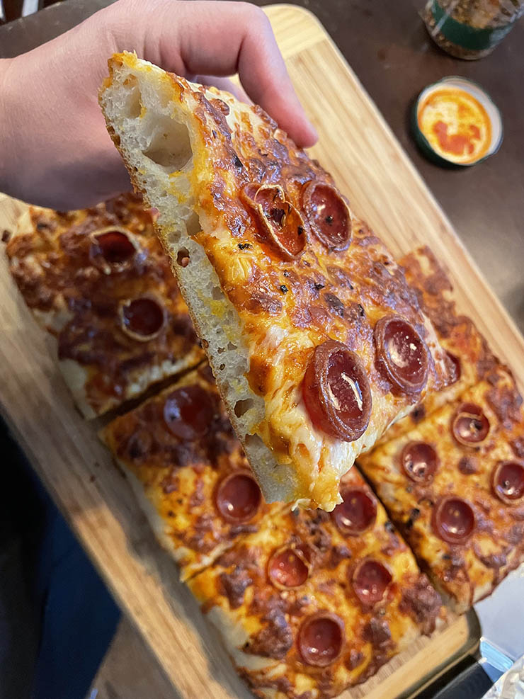 a man holding a slice of pepperoni pizza