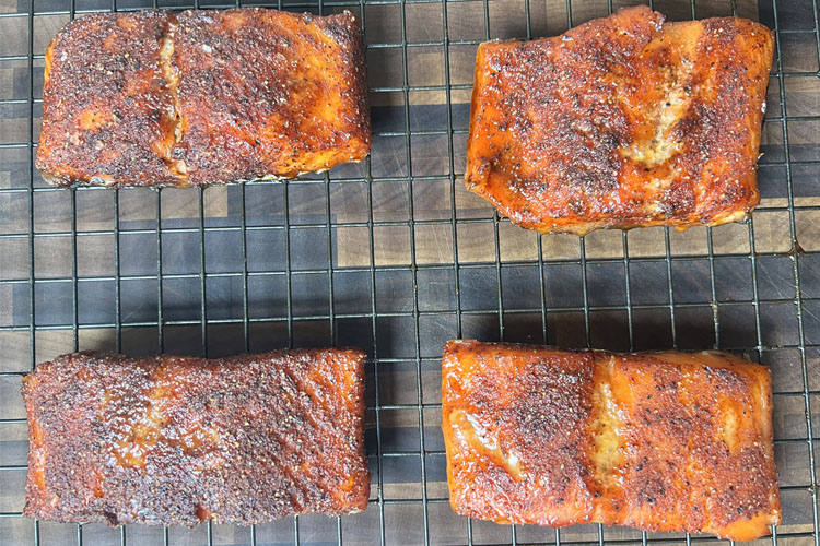 cooked slamon on a wire rack above a wooden chopping board