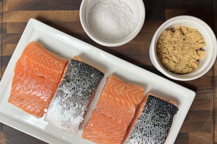 salmon on a white plate and brine ingredients in white bowls