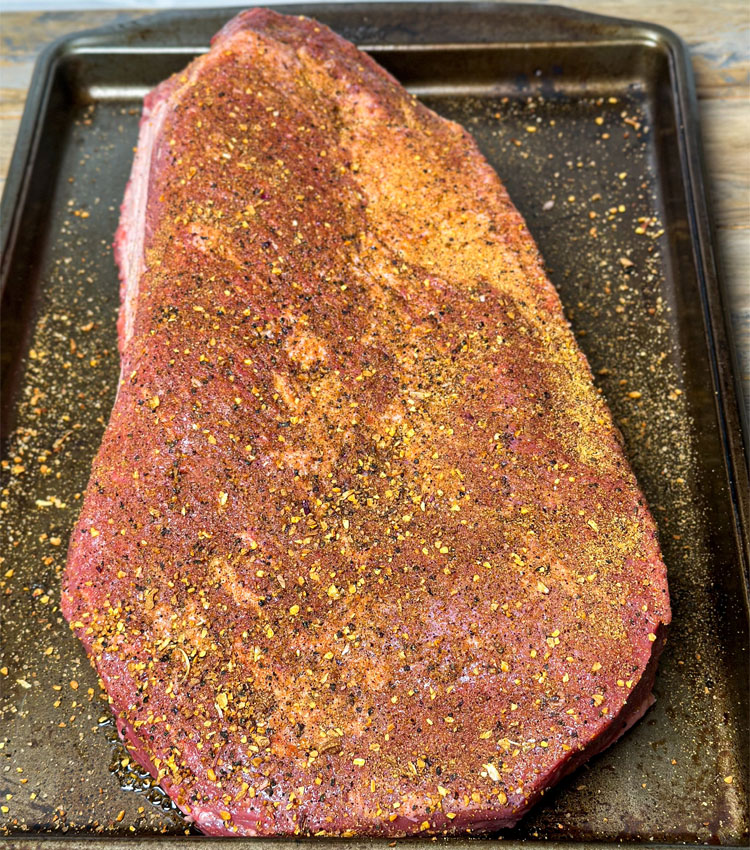 seasoned brisket in a metal baking dish