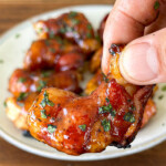 a hand holding a bacon wrapped shrimp