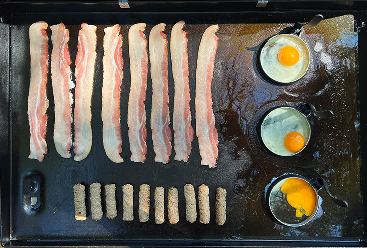 bacon, sausages and eggs cooking on the Weber Griddle