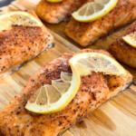 cedar plank grilled salmon fillets with lemon slices on top