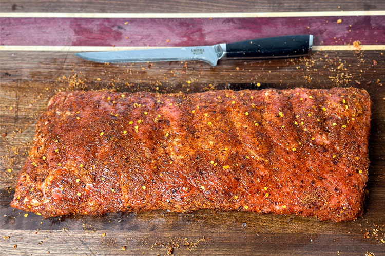 raw seasoned ribs on a wooden board