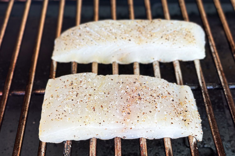 two pieces of raw halibut on the grill