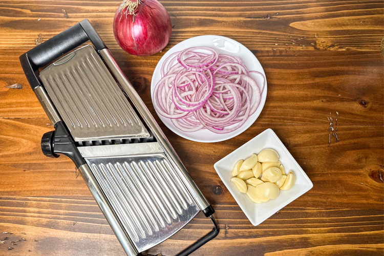 mandolin, red onion, sliced red onion on white plate, garlic on white plate