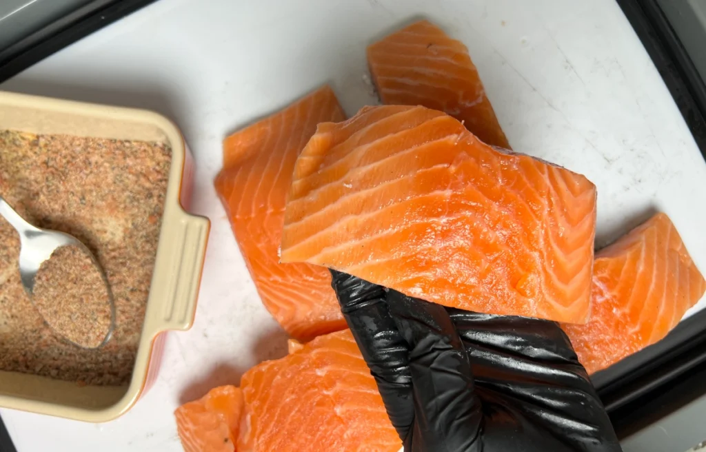 raw salmon being held by a black gloved hand