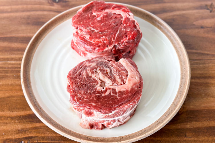 2 raw rolled rib eye cap on a white plate