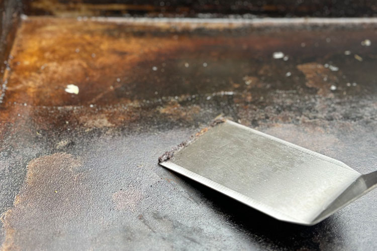 metal scraper getting the scraps off the griddle