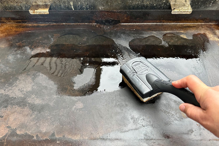 grill stone scrubbing a griddle with oil on it