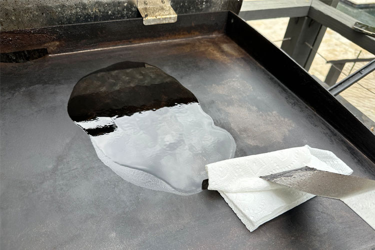 paper towel rubbing oil on the griddle