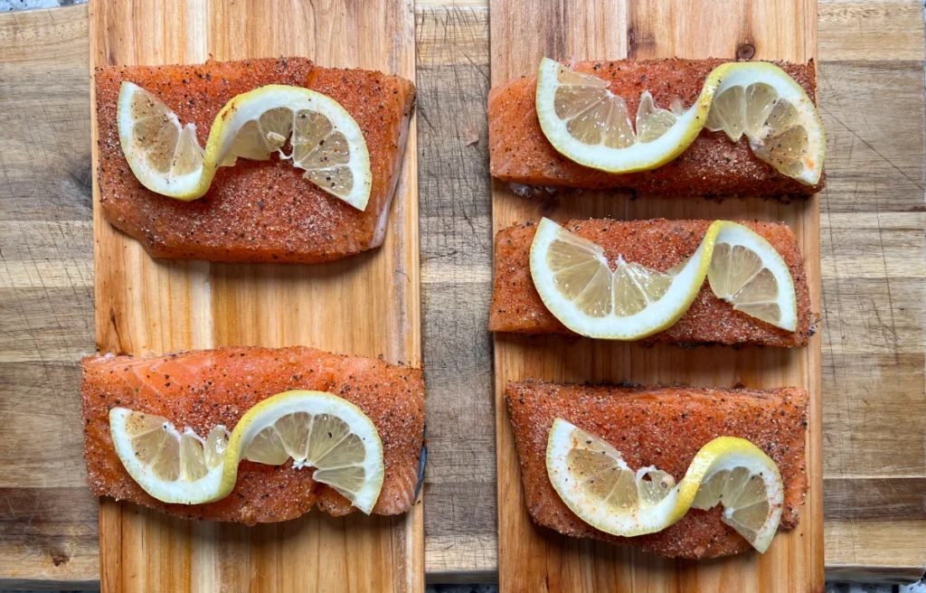 five salmon filets with lemon on top on cedar planks 