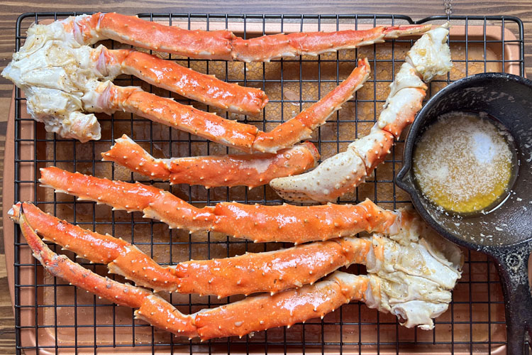 crab legs on a wire rack with a pot of butter sauce next to them