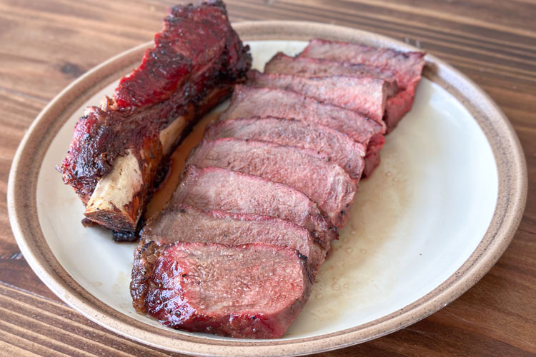 a sliced delmonico steak on a white plate