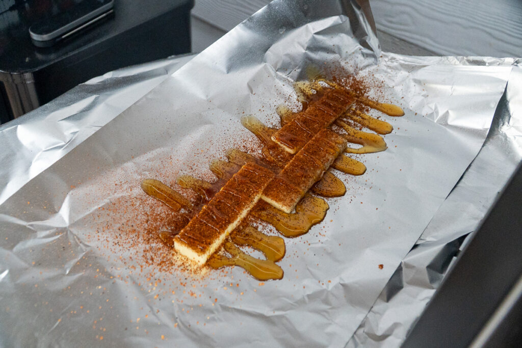 Strips of butter, honey, and BBQ seasoning arranged on a sheet of aluminum foil, ready for wrapping smoked ribs during the 3-2-1 method.