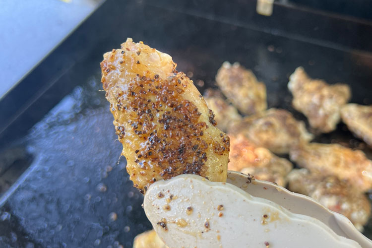 a cooked wingette being held with tongs