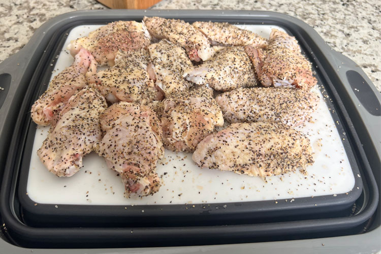 raw seasoned wings on a plastic board