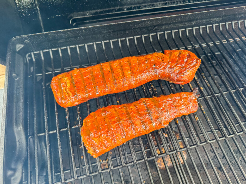 pork tenderloins with grill marks cooking on the smoker