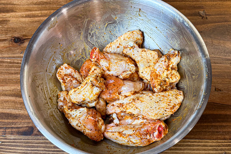 raw wings with seasoning in a metal bowl