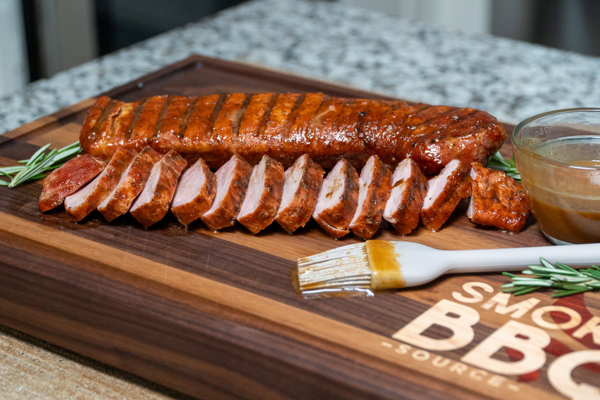 sliced smoked pork tenderloin on a wooden board