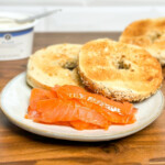 cold smoked salmon on a white plate served with toasted bagels