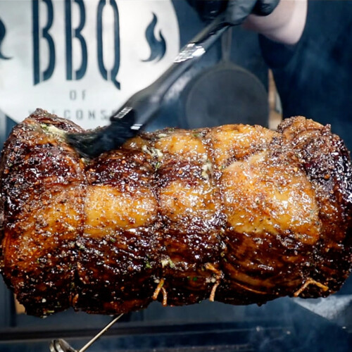 prime rib on a rotisserie being basted with butter and herbs