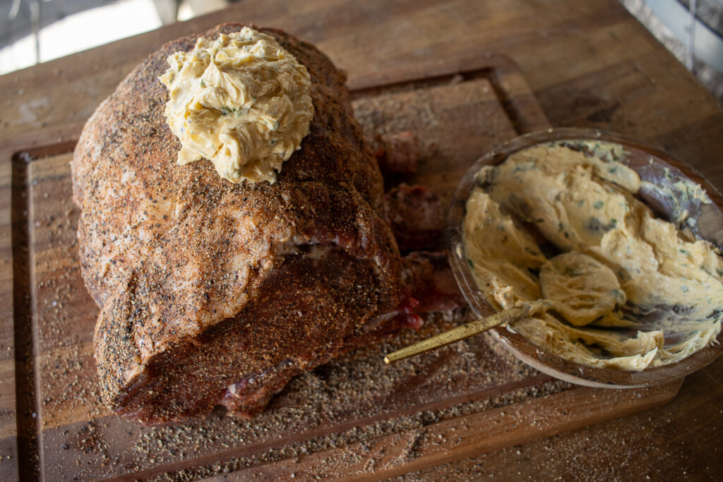 a raw prime rib being covered in compound butter