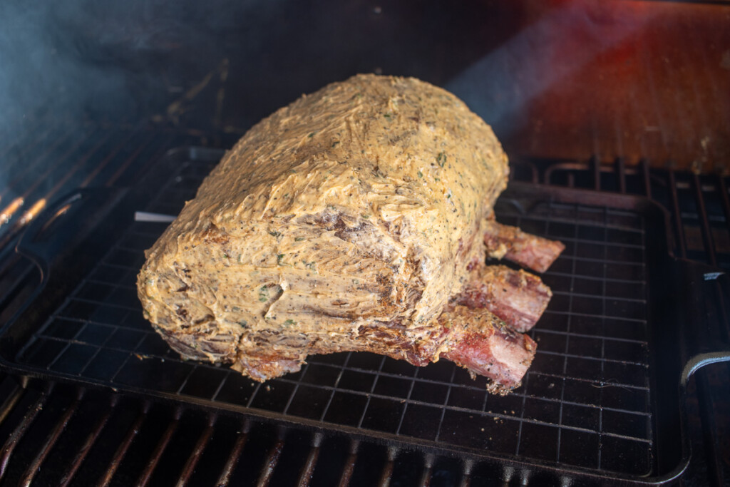a prime rib roast in the smoker covered in compound butter