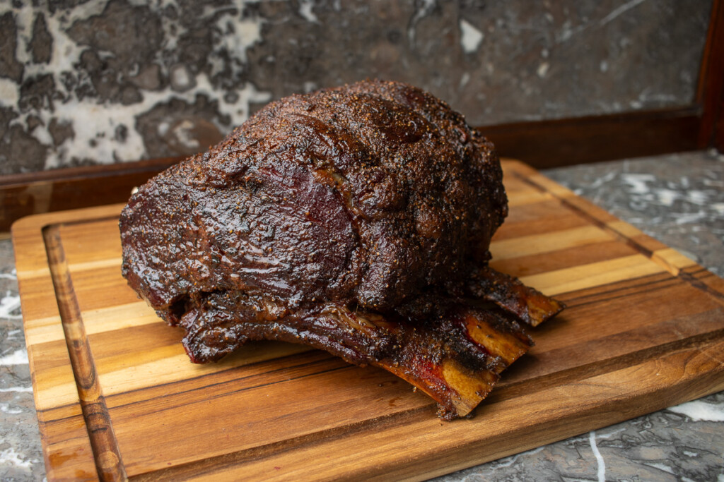 a prime rib roast resting on a wooden chopping board