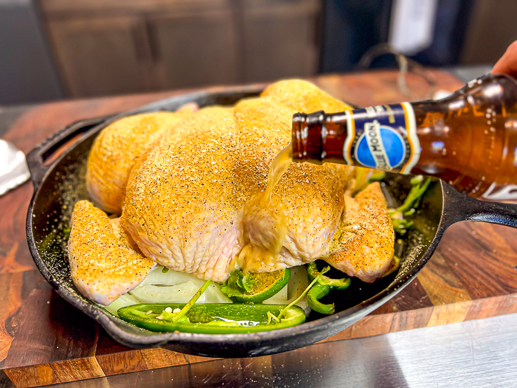 pouring blue moon beer around uncooked chicken in a skellet