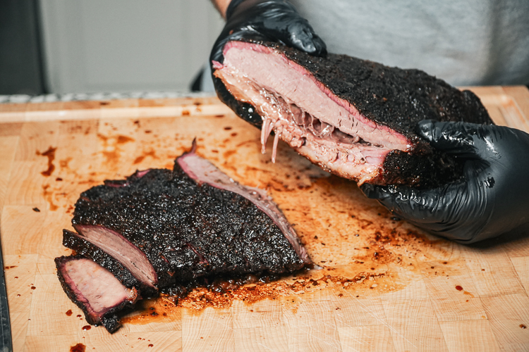 holding up a smoked brisket sliced in half