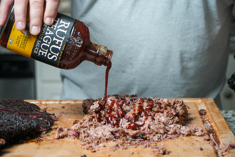 bbq sauce being poured onto chopped brisket