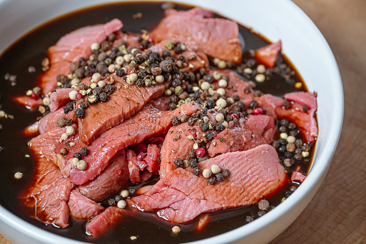peppered beef in marinade in white bowl
