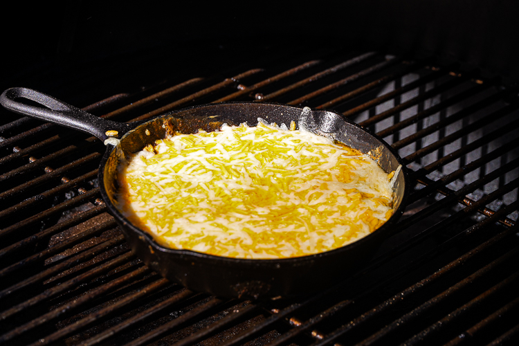 chili cheese dip with melted cheese on top in the smoker