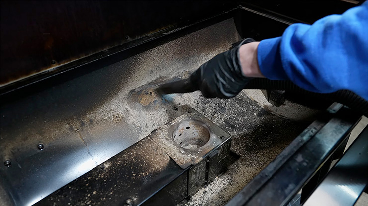 a man cleaning the Pit Boss Pro 1600 Elite pellet grill with a vacuum cleaner