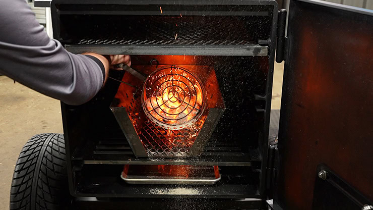 poring lit charcoal into Lone Star Grillz Offset Smoker fire management basket
