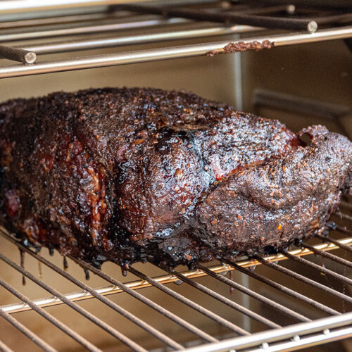 a cooked piece of no wrap pork butt on a shelf in the smoker