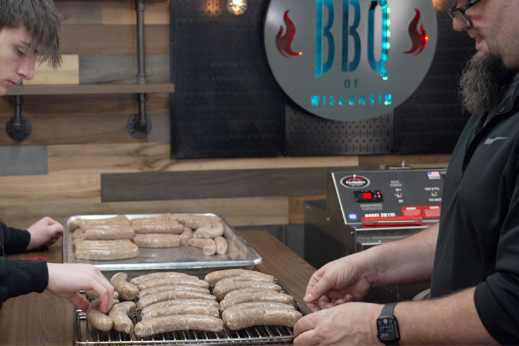 raw sausage being laid on racks to go in the smoker
