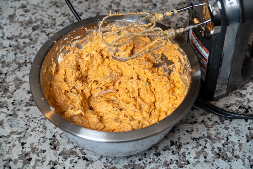 chicken buffalo dip in a metal bowl with electric  beaters