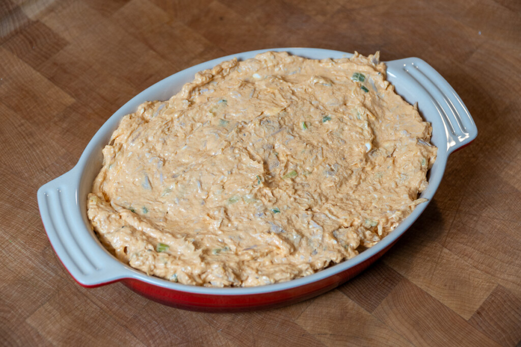 uncooked buffalo ranch dip in a red dish on a wooden chopping board