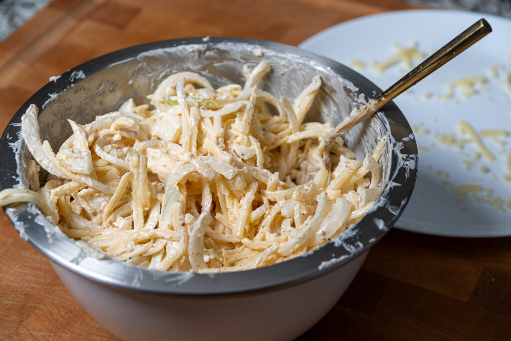 onions mixed with seasoning and mayonnaise in a metal bowl