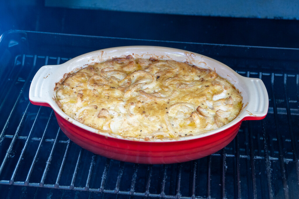 smoked onion dip in a red casserole dish in the smoker lightly brown on top