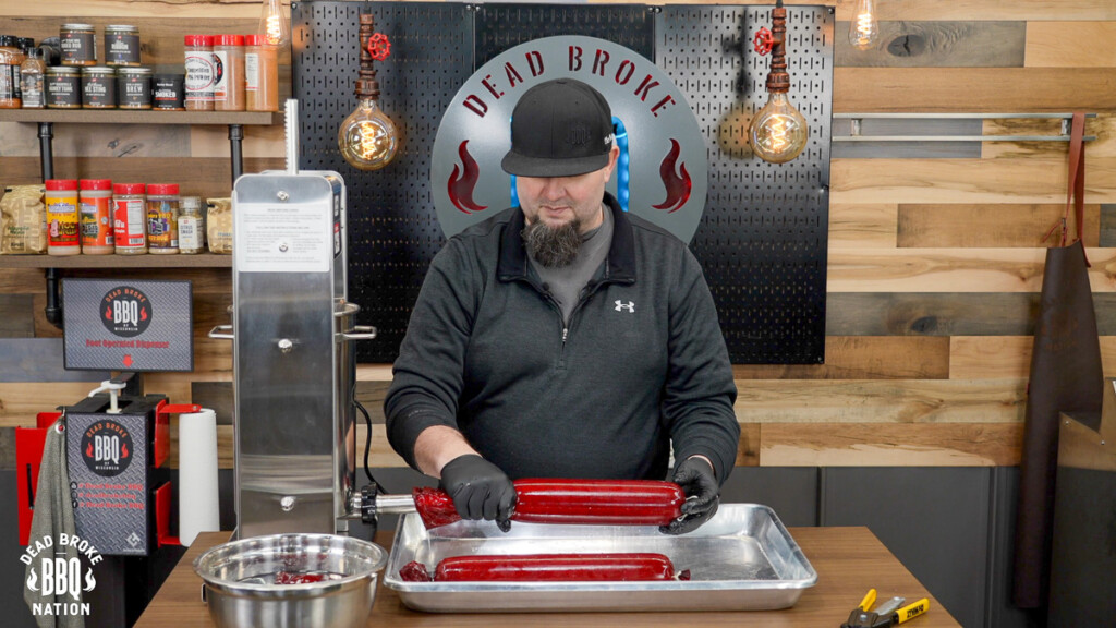 man holding casing as it is being filled with ground meat