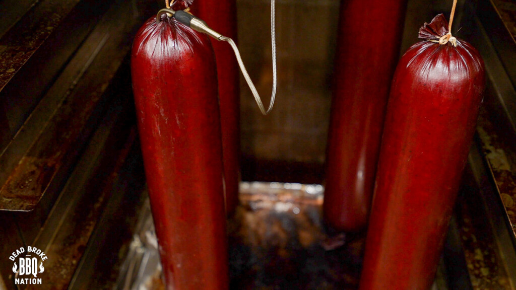 a summer sausage in the smoker with a temperature probe stuck in it