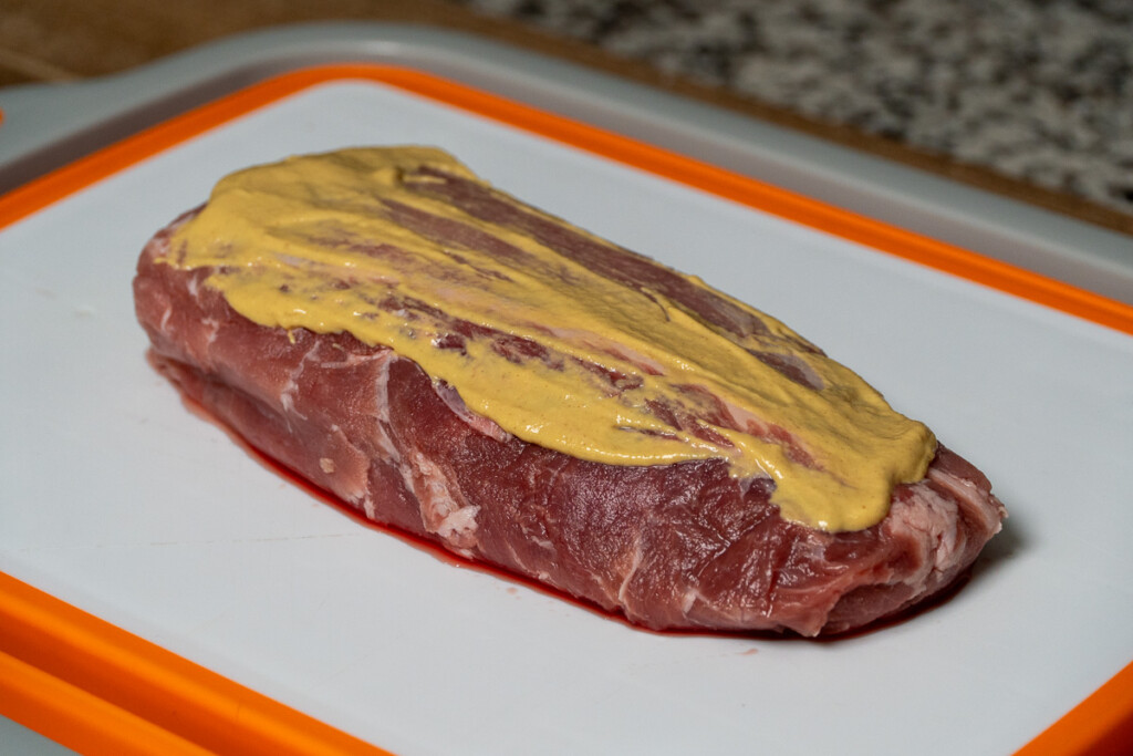 raw pork loin with dijon mustard on the top
